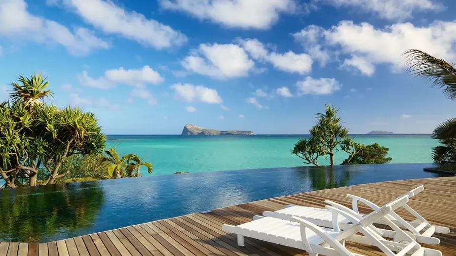 Infinity pool deck with sun loungers looking over the lagoon of Mauritius