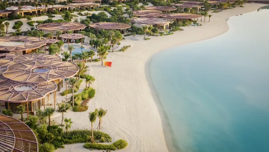 Raffles The Red Sea from above: pavilions with sculpted roofs along a white beach and a turquoise lagoon on Shura Island