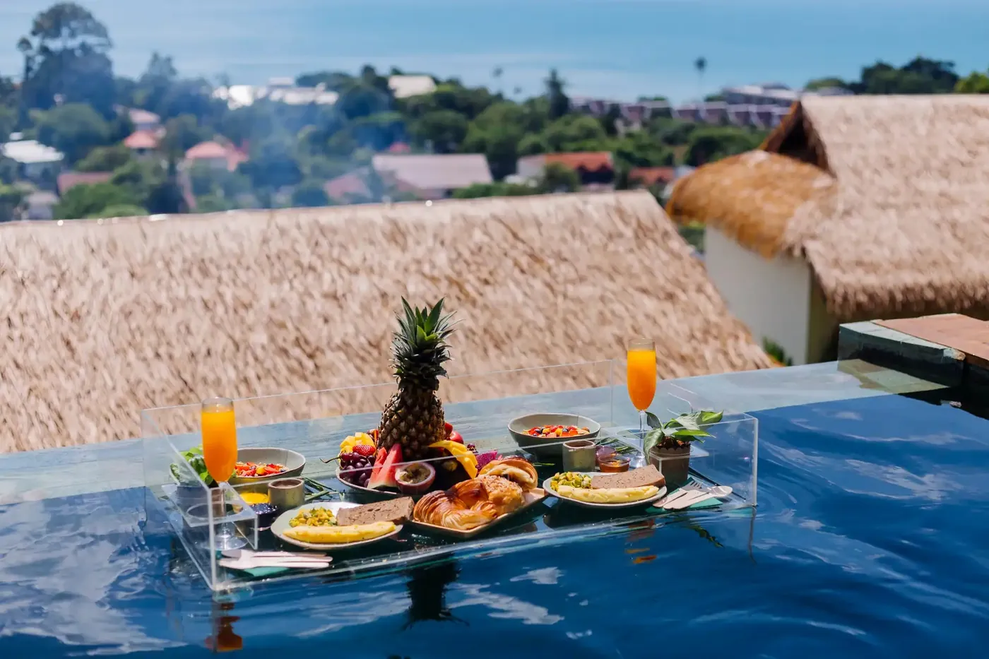 Floating breakfast tray in a villa pool under a thatched roof